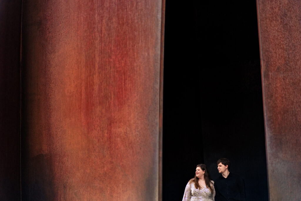 man and woman stand inside of large statue
