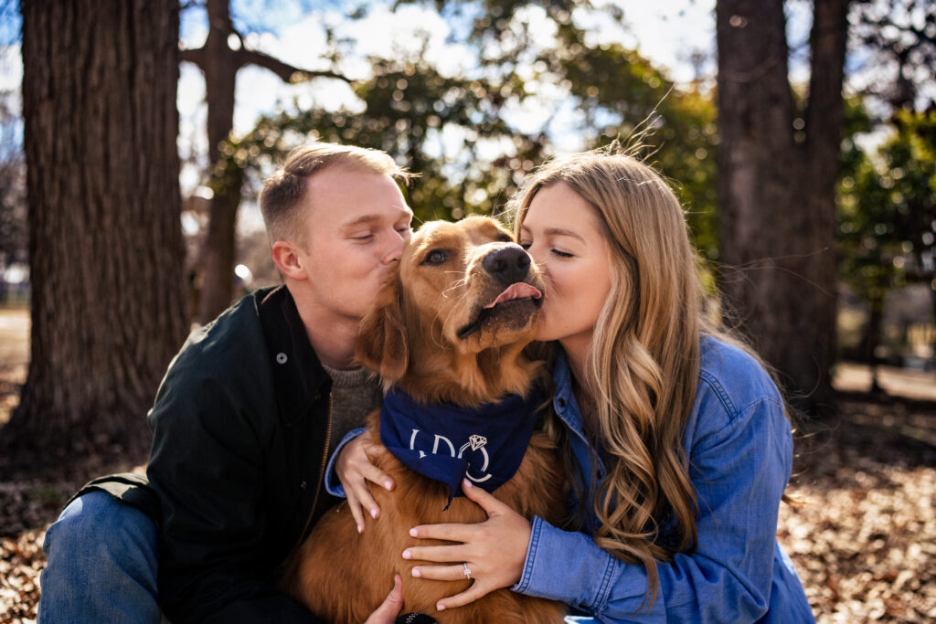 couple kisses the cheeks on their dogs