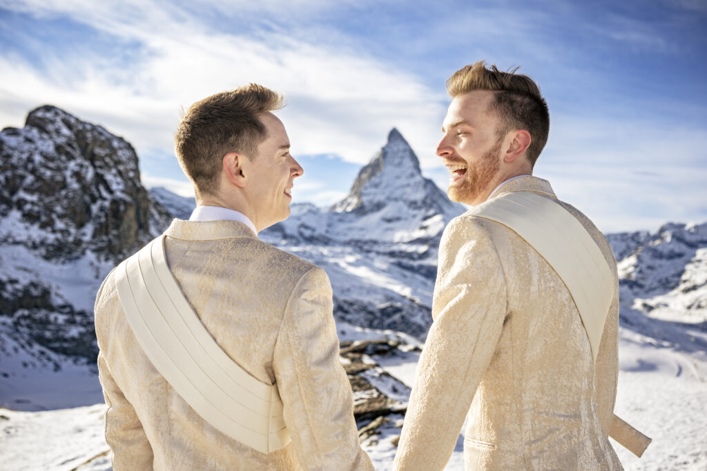 Matt & Brady in custom Don Morphy suits posing for LGBTQ wedding portraits at the Matterhorn in Zermatt, Switzerland with destination wedding photographers The MacMeekens