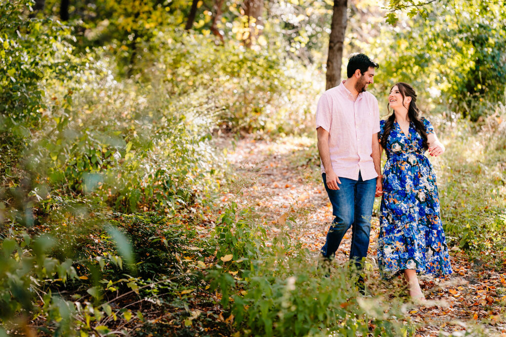 Couple walking on a sunlit trail during their Dallas engagement session at Reverchon Park.