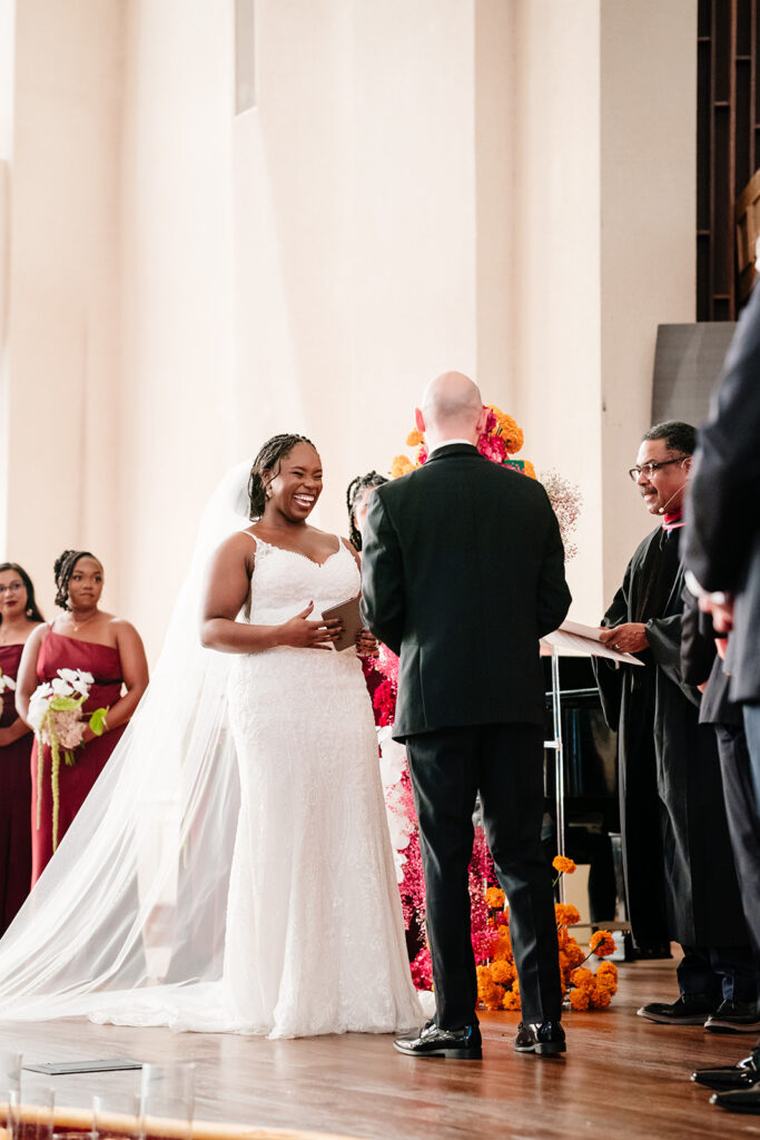 Ashley and Tom exchanging vows at Tyler Street Church in Dallas surrounded by stained glass windows