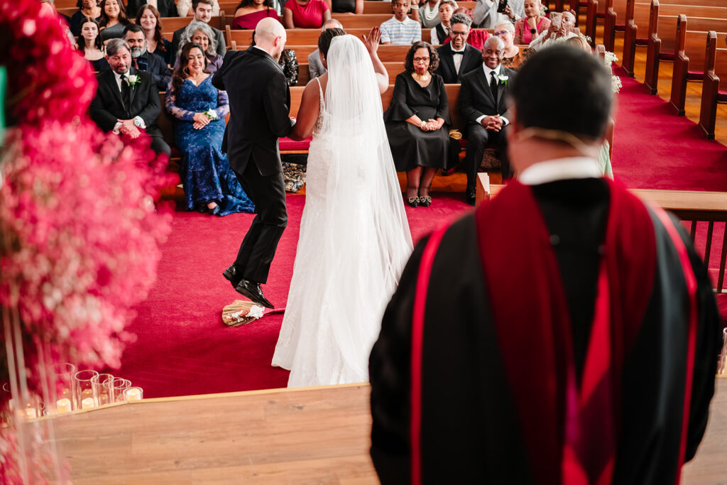 Bride and groom jumping the broom during their multicultural wedding ceremony at Tyler Street Church Dallas