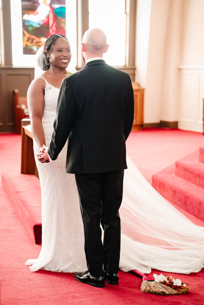 Ashley and Tom exchanging vows at Tyler Street Church in Dallas surrounded by stained glass windows