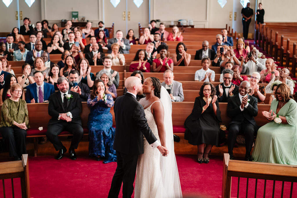 Bride and groom share first kiss after jumping the broom during their multicultural wedding ceremony at Tyler Street Church Dallas