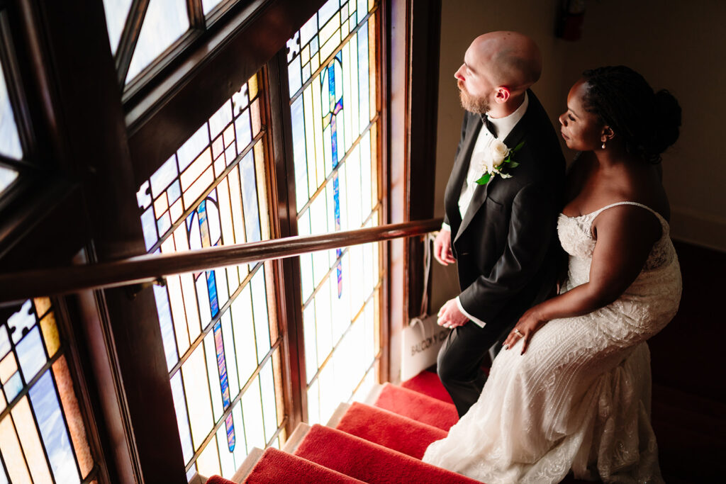 Bride and groom embracing beneath stained glass windows in Dallas