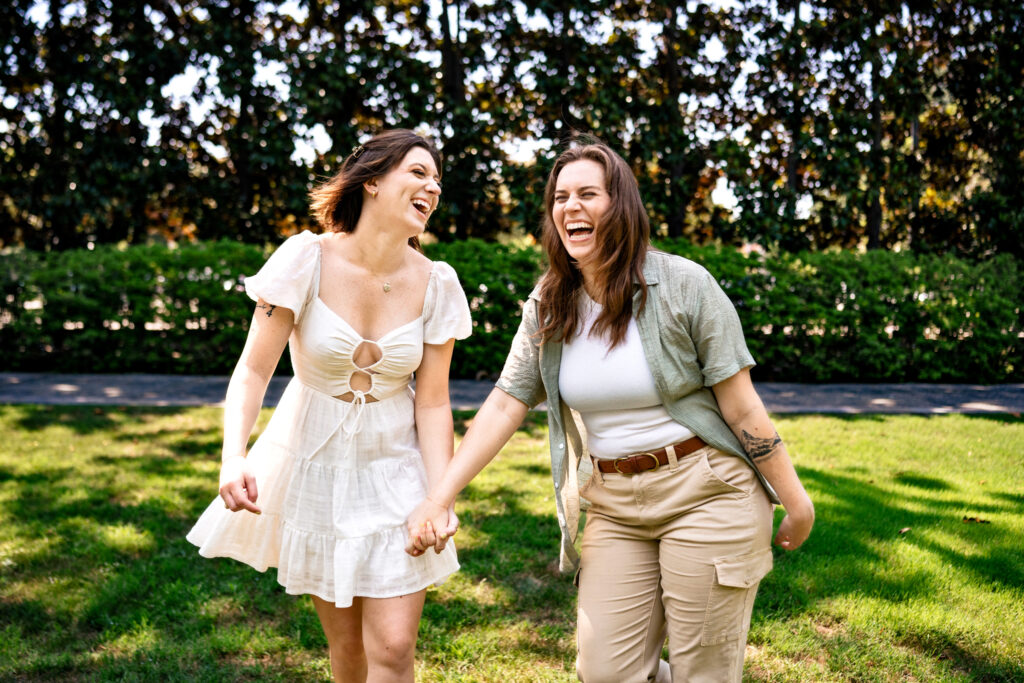 women walk together while holding hands and laughing