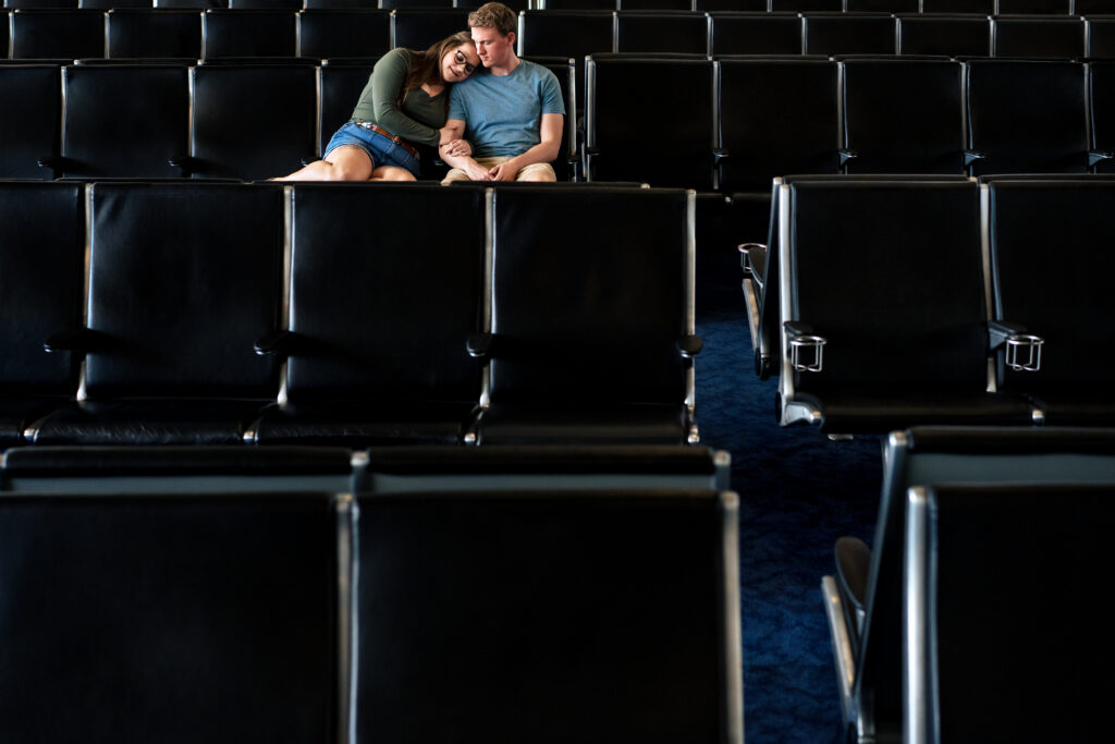 man and woman sit together in chairs at airport terminal gate