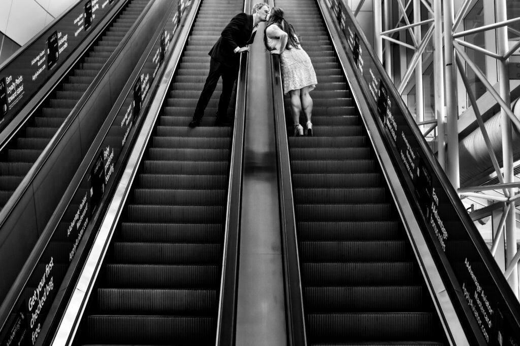 man and woman kiss while riding on escalator