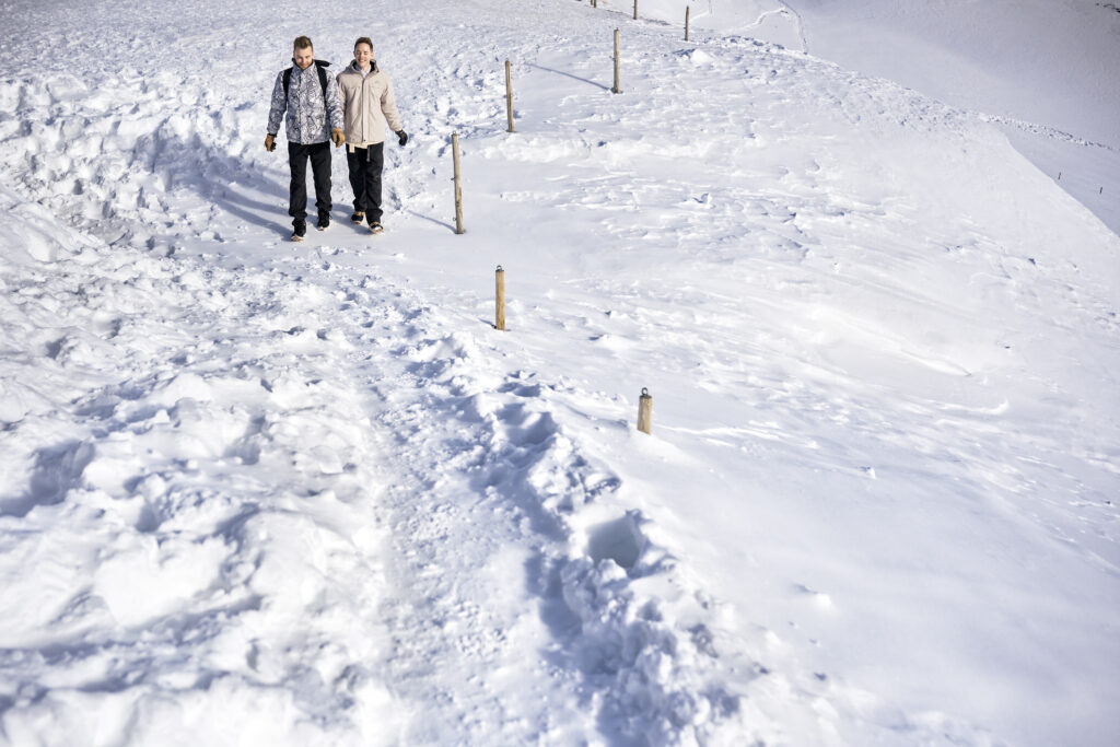 Matt & Brady laughing together in the snow during their adventurous LGBTQ wedding photography session in Zermatt, Switzerland