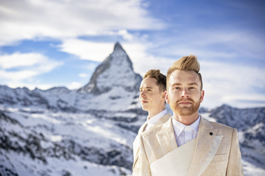 Matt & Brady in custom Don Morphy suits posing for LGBTQ wedding portraits at the Matterhorn in Zermatt, Switzerland with destination wedding photographers The MacMeekens