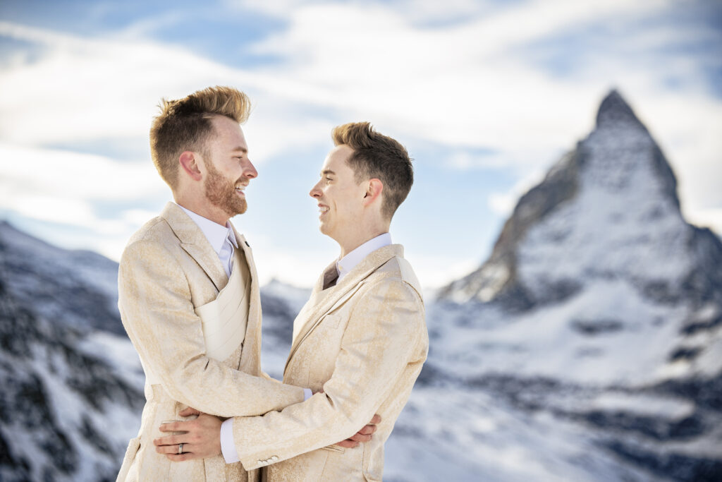 Matt & Brady in custom Don Morphy suits posing for LGBTQ wedding portraits at the Matterhorn in Zermatt, Switzerland with destination wedding photographers The MacMeekens