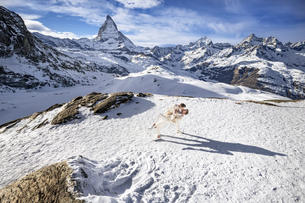 Matt & Brady standing in a snow-covered landscape with the Matterhorn in the background during their LGBTQ wedding portraits in Switzerland with documentary wedding photographers The MacMeekens