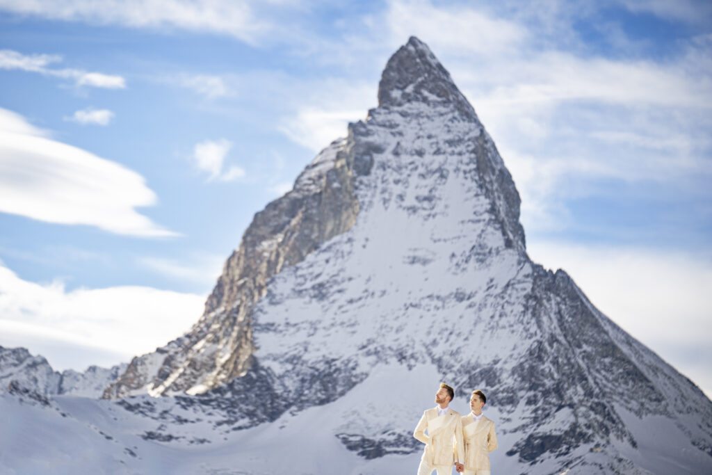 Matt & Brady standing in a snow-covered landscape with the Matterhorn in the background during their LGBTQ wedding portraits in Switzerland with documentary wedding photographers The MacMeekens