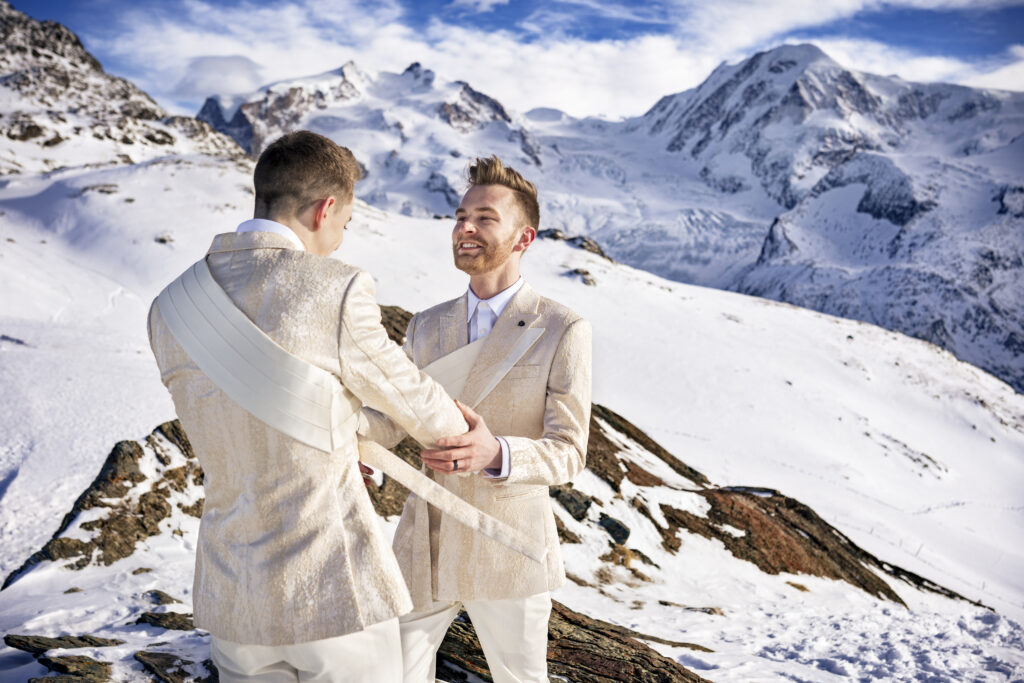 Matt & Brady in custom Don Morphy suits posing for LGBTQ wedding portraits at the Matterhorn in Zermatt, Switzerland with destination wedding photographers The MacMeekens